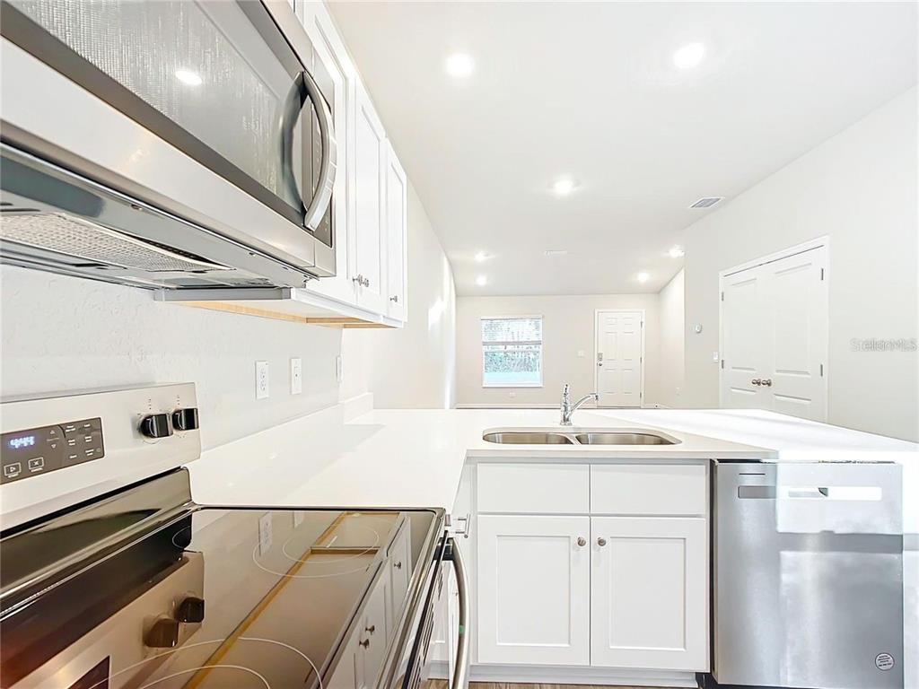 A kitchen features white cabinets, stainless steel appliances, and a double sink with white countertops — 3070 E ODIER STREET, INVERNESS, FL