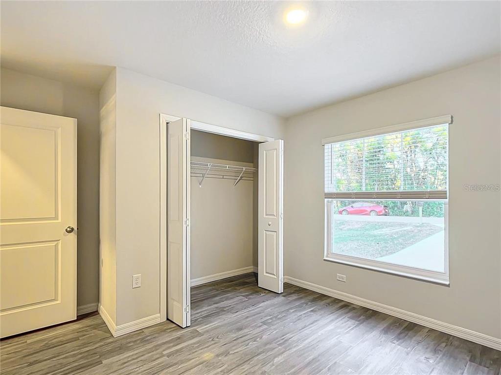 A bedroom features light gray walls, wood-look flooring, a closet with bifold doors, and a window — 3070 E ODIER STREET, INVERNESS, FL