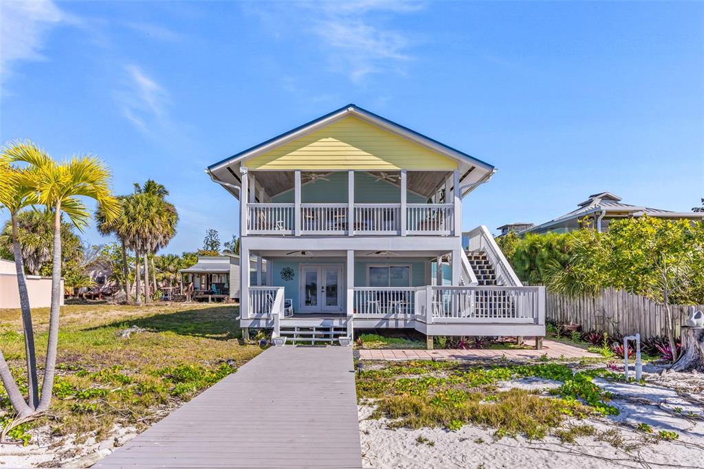 A two-story beach house with a raised deck, stairs, and a wooden walkway — 25 VIP ISLAND, GRANT, FL