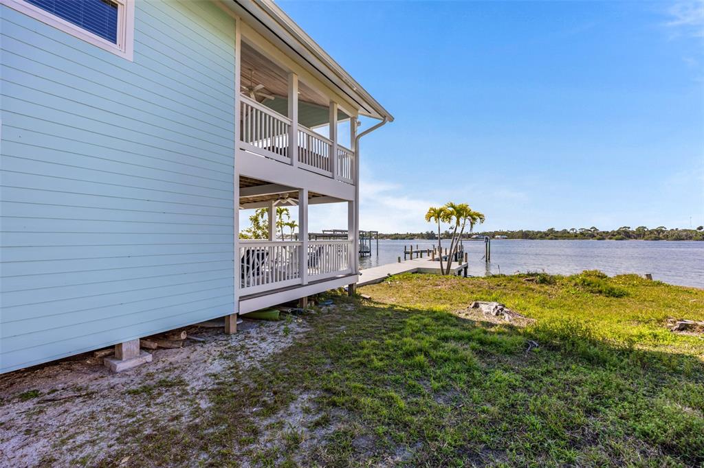 A light blue house with a two-story screened porch overlooks a dock and water — 25 VIP ISLAND, GRANT, FL