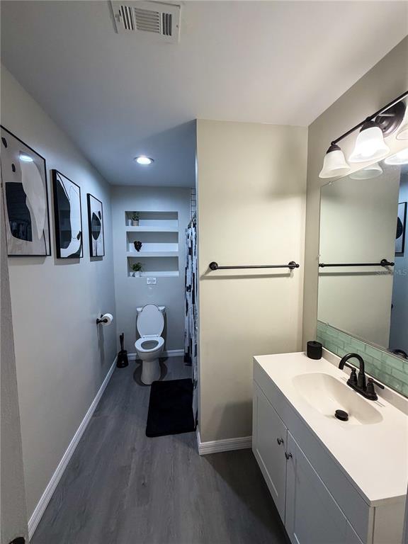 A bathroom features a white vanity, a toilet, built-in wall shelves, and gray flooring — 370 HAND AVE, ORMOND BEACH, FL