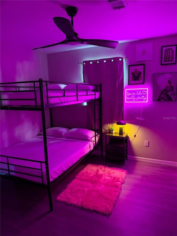 A bedroom features a black metal bunk bed, a pink neon sign, and purple lighting — 370 HAND AVE, ORMOND BEACH, FL