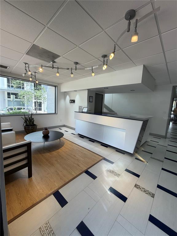 A modern office reception area features a white desk, track lighting, and a wood-floored lounge — 330 E CENTRAL BOULEVARD, ORLANDO, FL