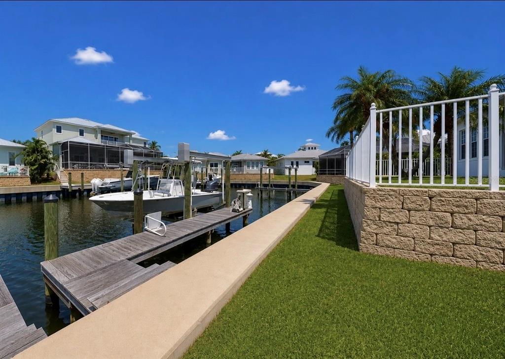 A boat is docked at a wooden pier next to a grassy lawn and retaining wall — 611 MIRABAY BOULEVARD, APOLLO BEACH, FL