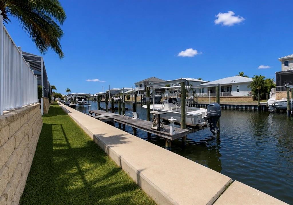A concrete seawall borders a canal with boat docks and several moored motorboats — 611 MIRABAY BOULEVARD, APOLLO BEACH, FL