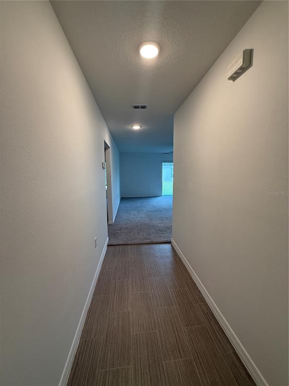 A hallway with tile flooring leads to a carpeted living area with recessed lighting — 46 WILLOW LANE, POINCIANA, FL