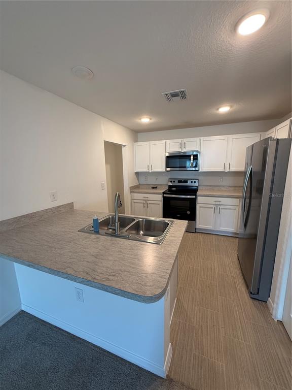 A kitchen with white cabinets, stainless steel appliances, and a gray laminate countertop island — 46 WILLOW LANE, POINCIANA, FL