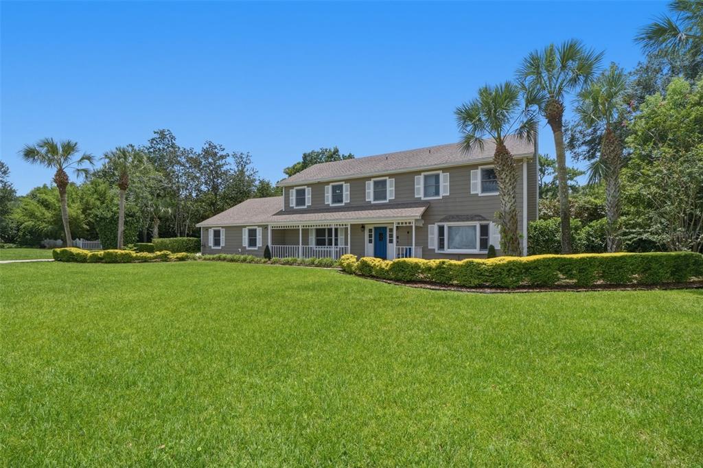 A two-story house with gray siding, a blue front door, and a large front lawn — 2143 BLUE IRIS PLACE, LONGWOOD, FL