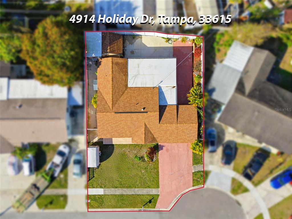 An aerial view shows a residential house with a brown shingled roof and driveway — 4914 HOLIDAY DRIVE, TAMPA, FL