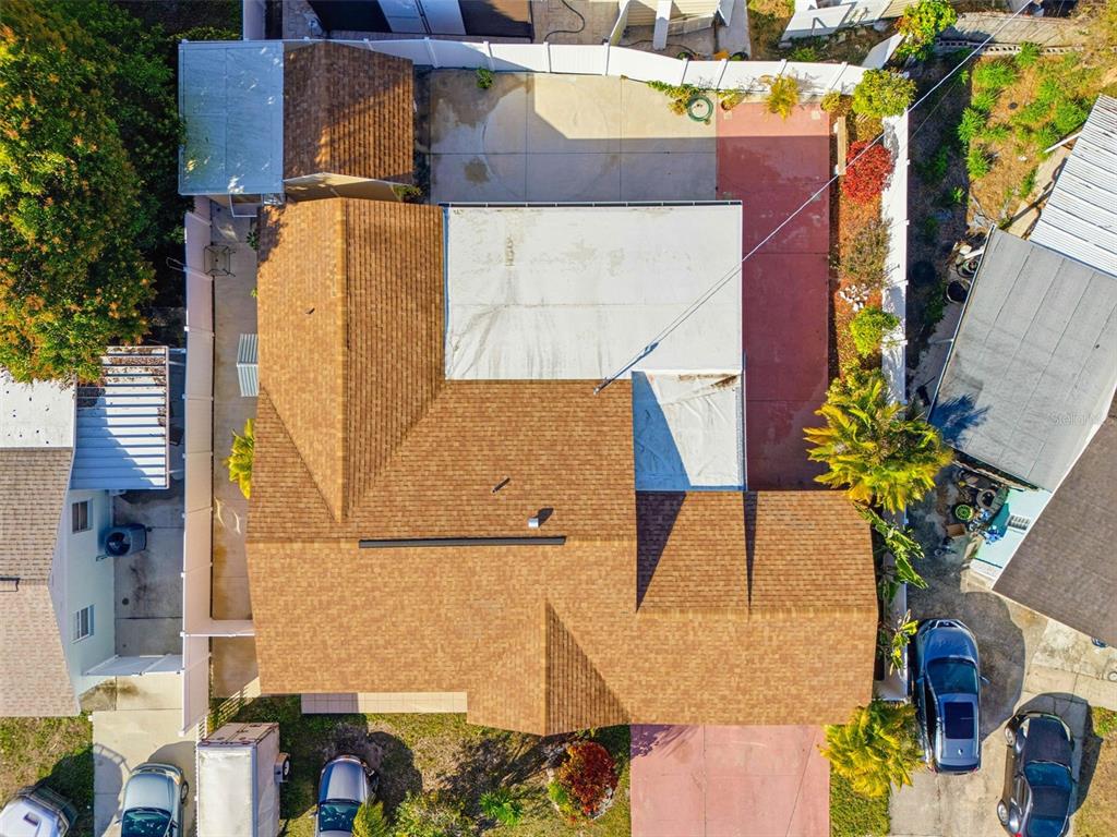 An aerial view shows a house with a brown shingled roof and a flat white roof — 4914 HOLIDAY DRIVE, TAMPA, FL