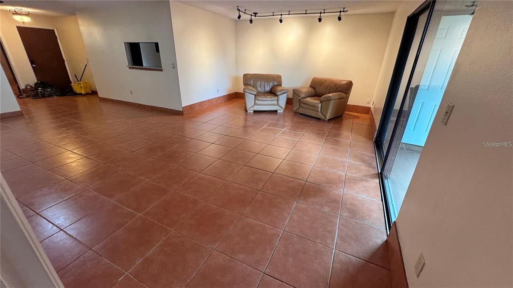 A living room features tan tile flooring, two leather armchairs, and track lighting — 2657 EXUMA WAY, WINTER PARK, FL
