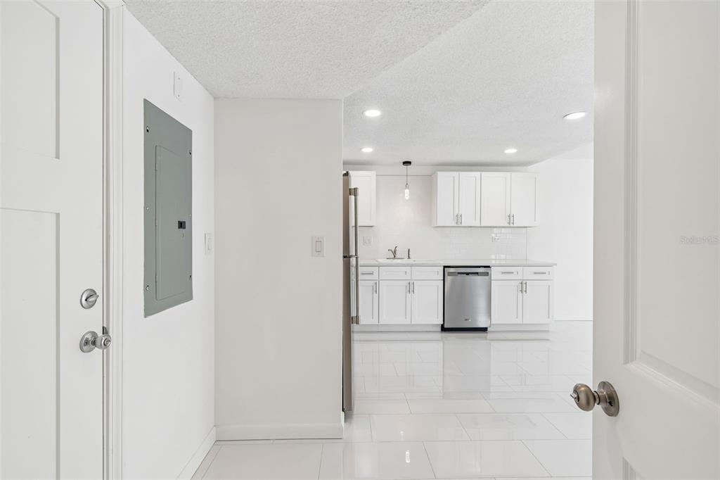A virtually staged living room features a blue sectional, light wood console, and sliding glass doors — 450 TREASURE ISLAND CAUSEWAY UNIT 106, TREASURE ISLAND, FL