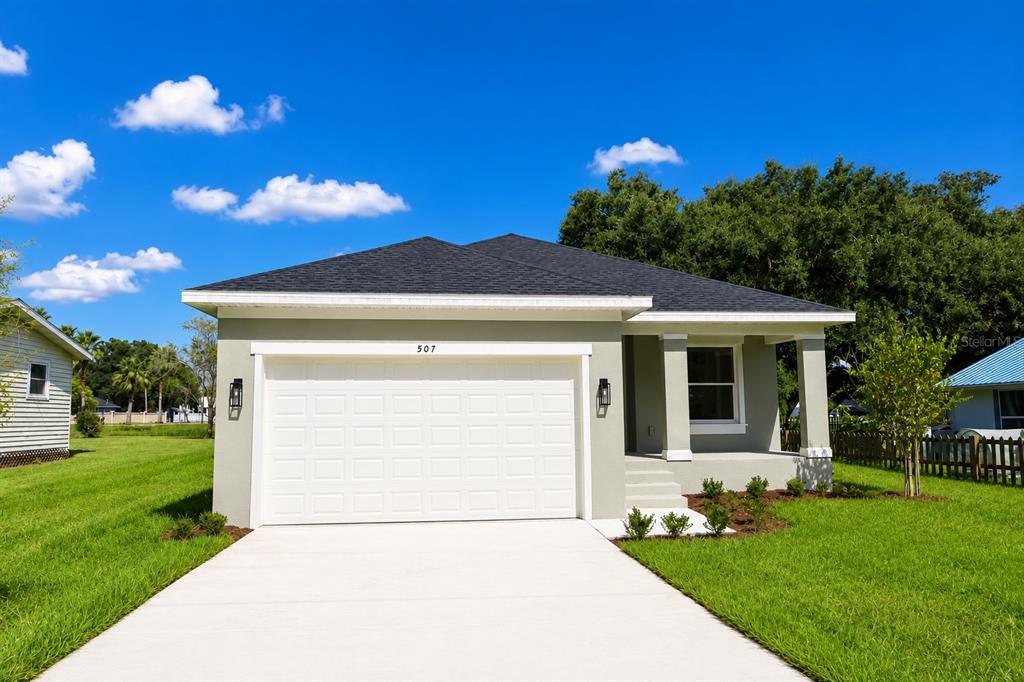 A single-story house with a white garage door, light green siding, and a dark roof — 507 FINLEY AVENUE, KISSIMMEE, FL