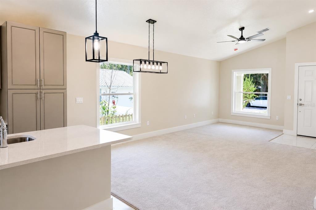 A kitchen with light cabinets and a quartz island overlooks an open carpeted living area — 507 FINLEY AVENUE, KISSIMMEE, FL
