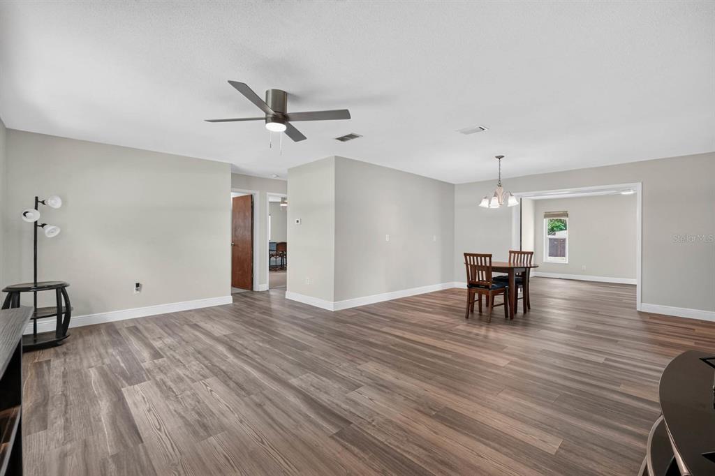 An open-concept living and dining area features light gray walls and wood-look laminate flooring — 2205 JUNIPER DRIVE, EDGEWATER, FL