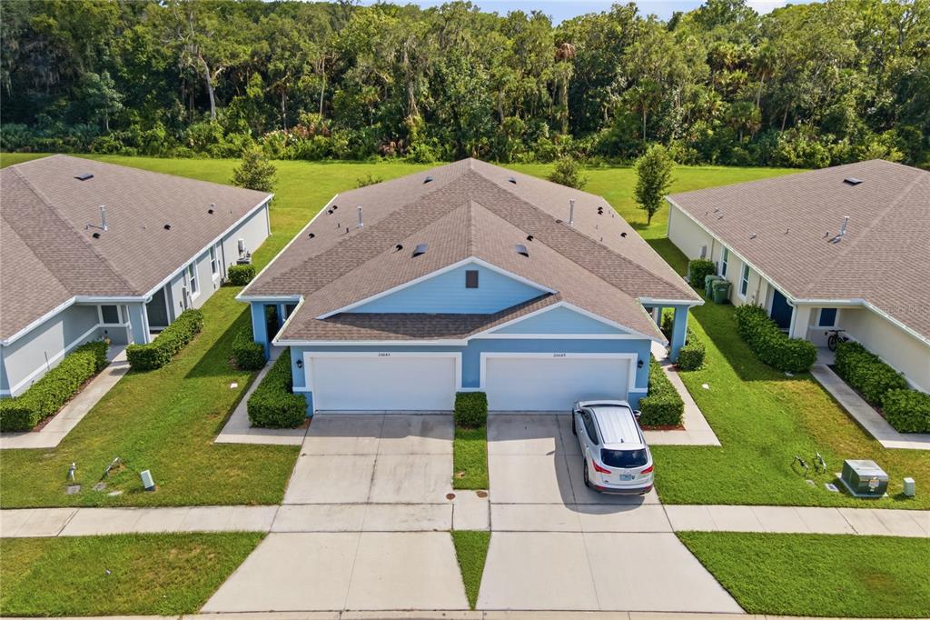 An aerial view of a blue duplex with two garages and a shared driveway — 20043 ROYAL TERN COURT, LEESBURG, FL