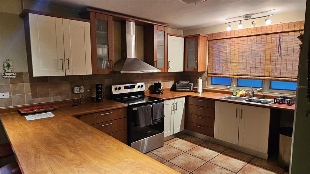 A kitchen features two-toned wood and cream cabinets, a stainless steel range, and wood countertops — C-201 PALMA VISTA COND, FAJARDO, PR