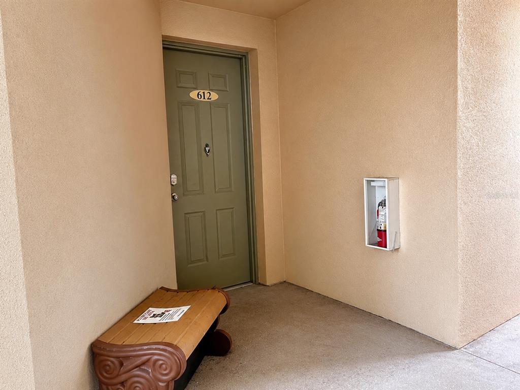 A green apartment door numbered 612 with a bench and fire extinguisher in the hallway — 612 TERRACE RIDGE CIRCLE UNIT 126, DAVENPORT, FL