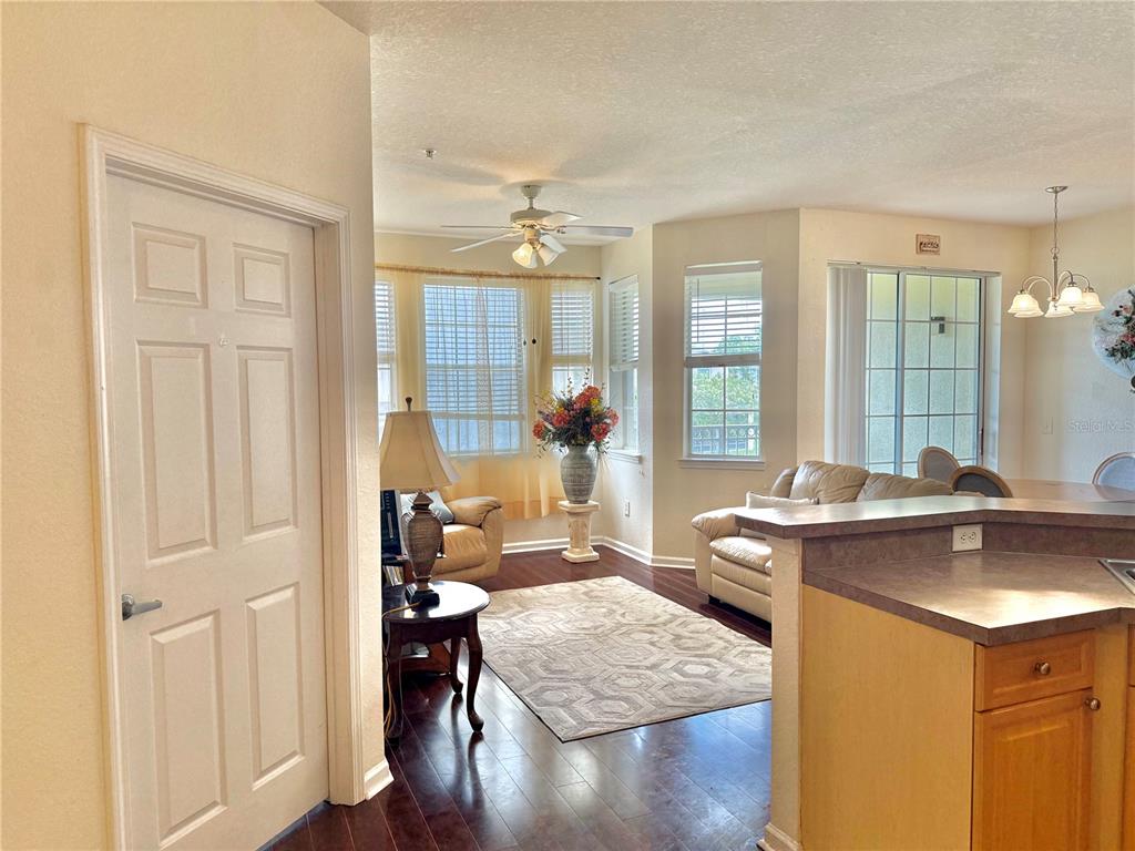 A living room with hardwood floors, a ceiling fan, and a view into the kitchen — 612 TERRACE RIDGE CIRCLE UNIT 126, DAVENPORT, FL
