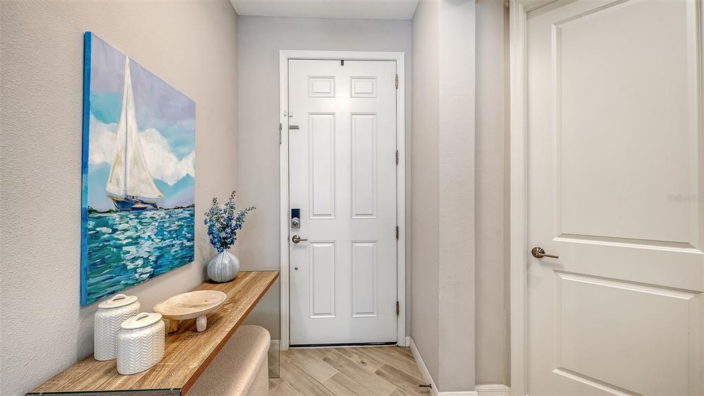 An entryway features a white door, a wooden console table, and a sailboat wall painting — 15336 ISLA PALMA LANE, NOKOMIS, FL