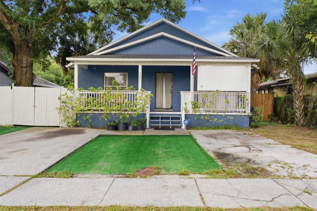 A blue single-story house with a front porch, artificial turf, and a concrete driveway — 3203 DELEUIL AVENUE, TAMPA, FL