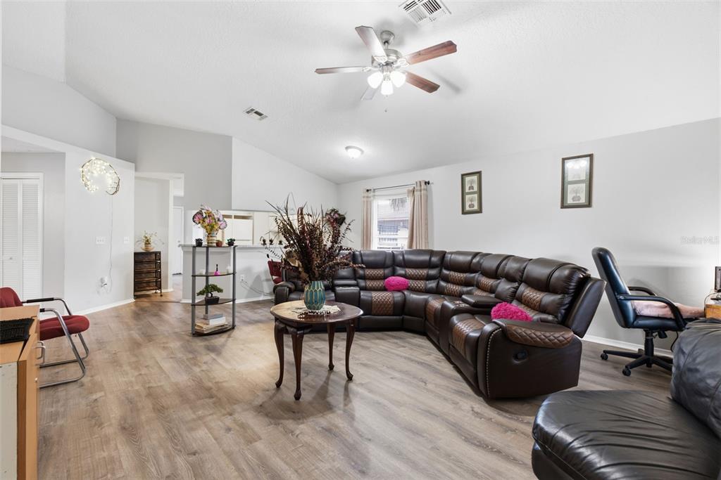A living room features wood-look flooring, a large brown sectional sofa, and a ceiling fan — 3203 DELEUIL AVENUE, TAMPA, FL