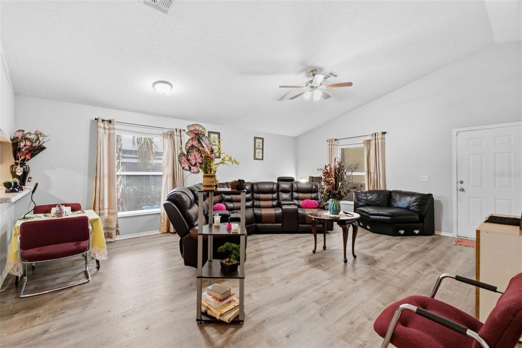 A living room features wood-look flooring, a dark sectional sofa, and a dining area — 3203 DELEUIL AVENUE, TAMPA, FL