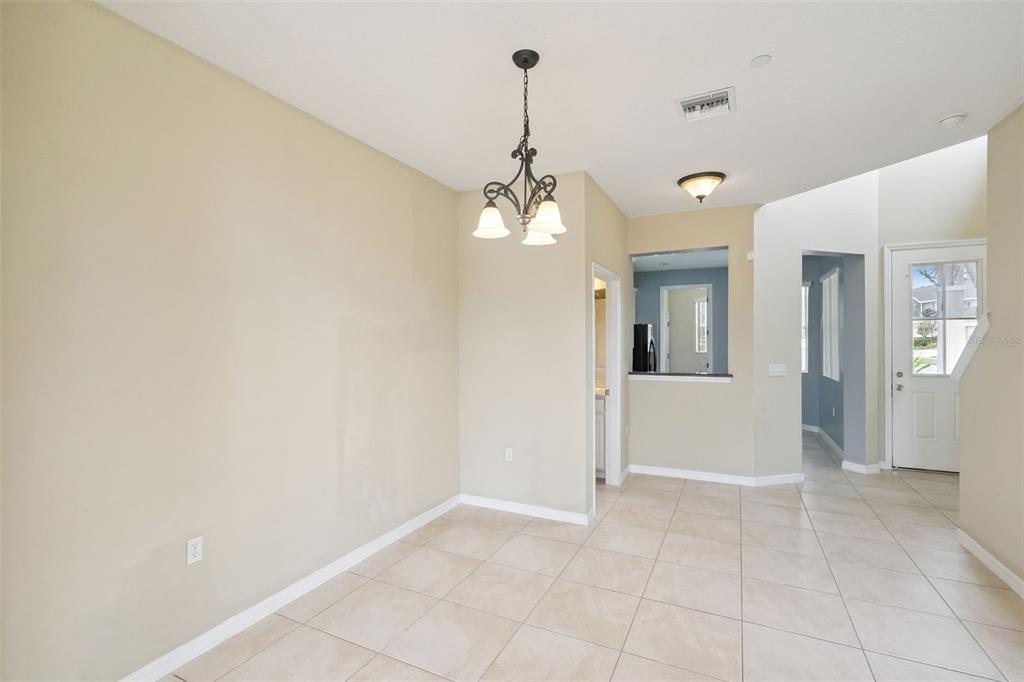 An empty dining area features beige walls, tile flooring, and a hanging light fixture — 722 CHACALL LOOP, MOUNT DORA, FL