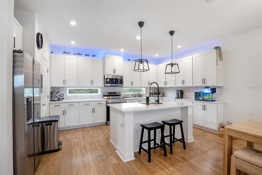 A modern kitchen with a white island and stainless steel appliances overlooks a dining area — 7251 NEMOURS PARKWAY, ORLANDO, FL