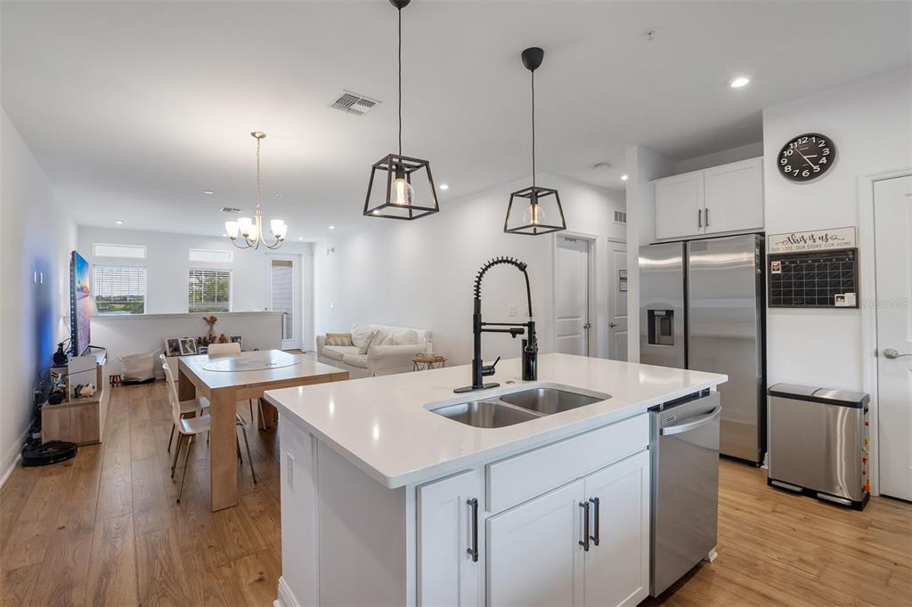 A modern kitchen features white cabinetry, stainless steel appliances, a central island, and wood flooring — 7251 NEMOURS PARKWAY, ORLANDO, FL
