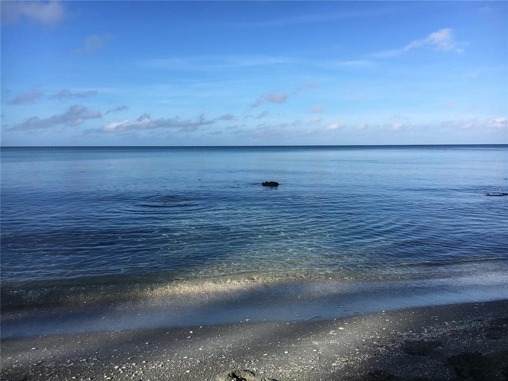 A view of the ocean with waves breaking over rocks on a sandy beach — 7740 SANDERLING ROAD, SARASOTA, FL