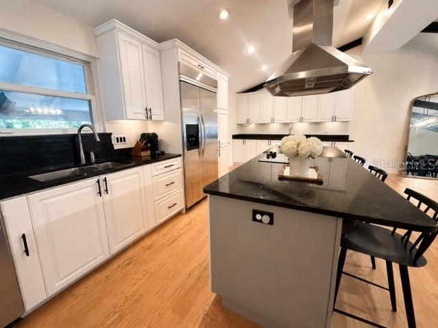 A modern kitchen features white cabinetry, a large black island, and stainless steel appliances — 1909 OLD SAWMILL ROAD, BRANDON, FL