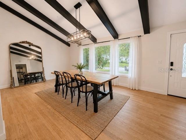 A dining room features a wooden table, black chairs, a large mirror, and exposed ceiling beams — 1909 OLD SAWMILL ROAD, BRANDON, FL