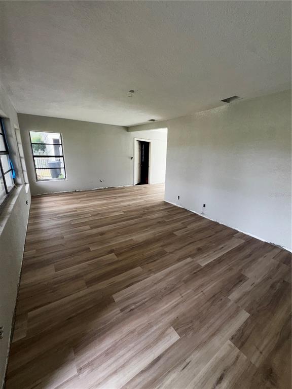 An empty room features light-colored walls, wood-look flooring, and a window overlooking the exterior — 3249 54TH STREET N, ST PETERSBURG, FL