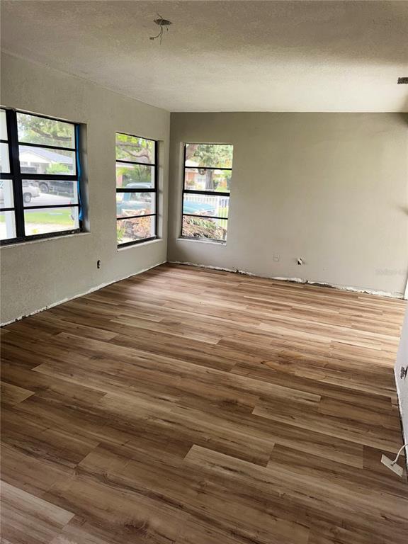 An empty room with light wood-look flooring, gray walls, and three windows — 3249 54TH STREET N, ST PETERSBURG, FL