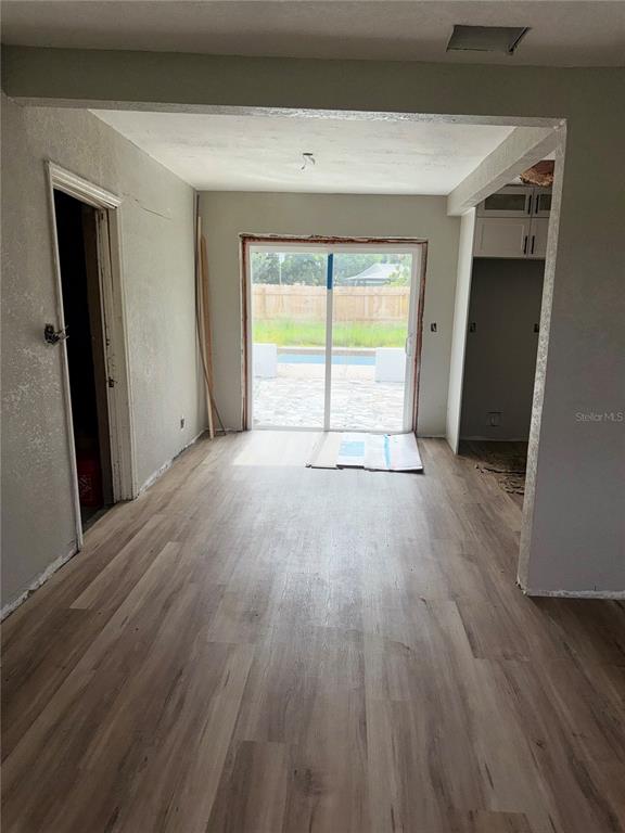 An interior room features light wood-look flooring, gray walls, and a sliding glass door to a patio — 3249 54TH STREET N, ST PETERSBURG, FL