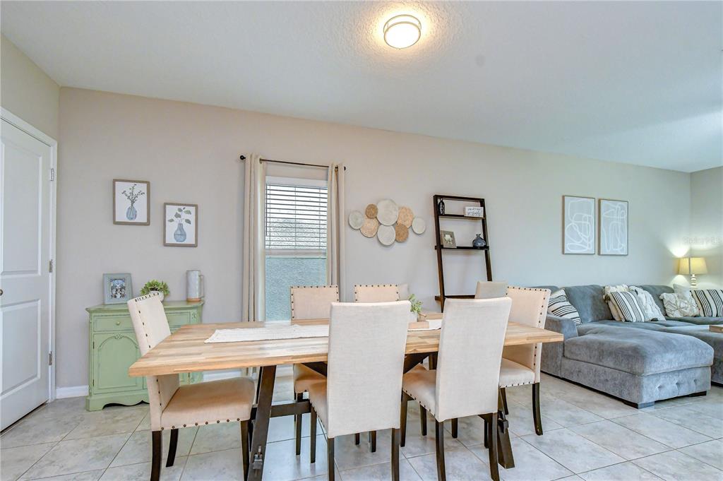 A dining area with a wooden table and chairs sits adjacent to a living room — 17917 CLOUDLESS BLISS DRIVE, LUTZ, FL