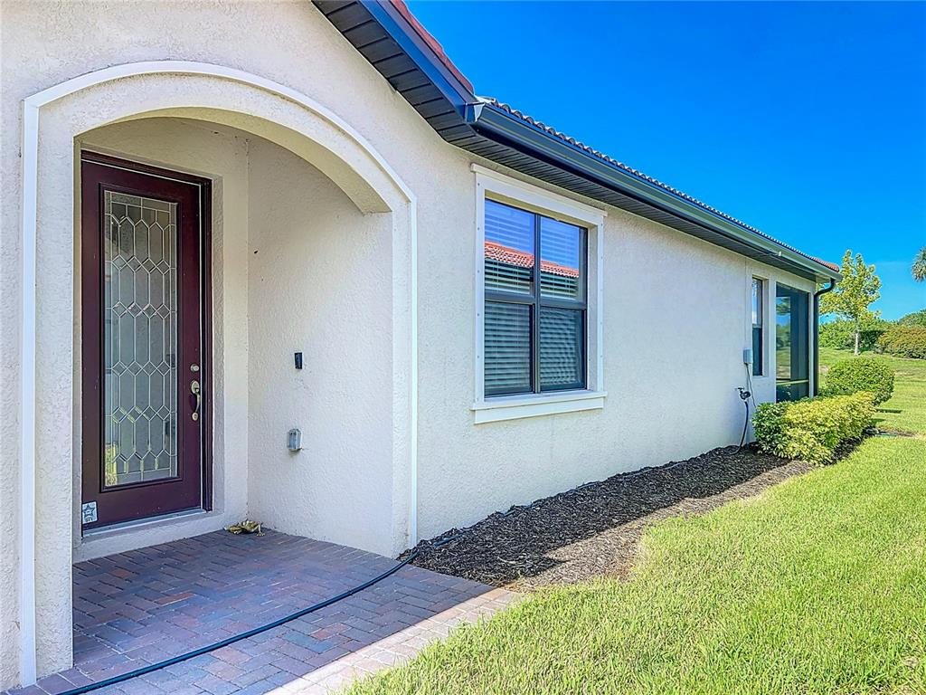 The exterior of a house features a brick porch, a dark door, and a window — 24137 SPARTINA DRIVE, VENICE, FL