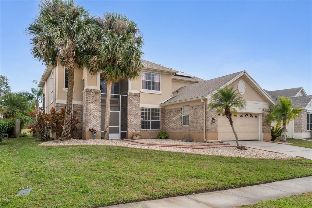 A two-story house with a brick facade, a two-car garage, and palm trees in front — 1524 THE OAKS BOULEVARD, KISSIMMEE, FL