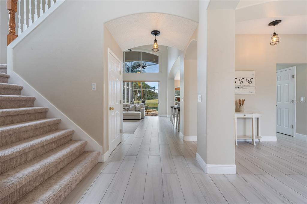 A carpeted staircase leads to an arched hallway with tile flooring and a view outdoors — 1524 THE OAKS BOULEVARD, KISSIMMEE, FL