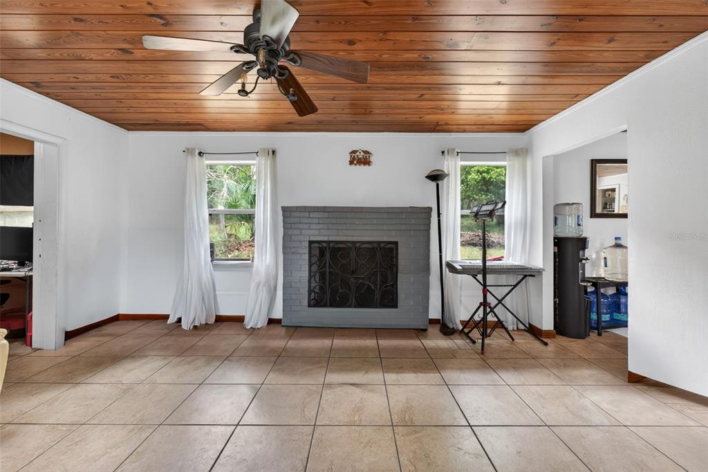 A living room features a gray brick fireplace, tile flooring, and a wood-paneled ceiling — 8023 STONE ROAD, APOPKA, FL