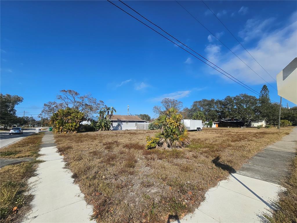 A vacant corner lot with dry grass, a few palm trees, and a house nearby — 132ND AVENUE, SEMINOLE, FL
