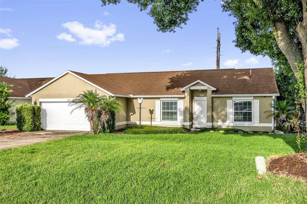 A single-story house with a white garage, brown roof, and a green front lawn — 418 GROVEPARK DRIVE, DAVENPORT, FL
