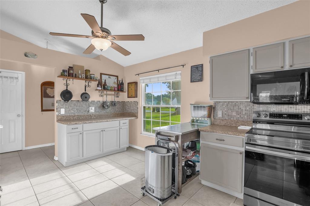 A kitchen with light gray cabinets, tile flooring, a ceiling fan, and a window — 418 GROVEPARK DRIVE, DAVENPORT, FL