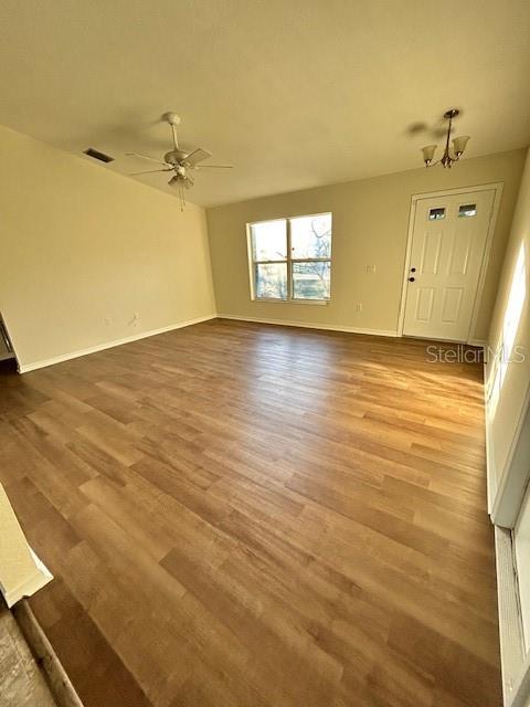 An empty room features light wood-look flooring, a ceiling fan, and a white entry door — 5814 BRICKELL DRIVE, NORTH PORT, FL