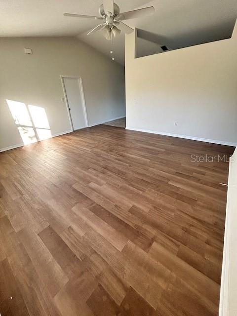 An empty room features wood-look flooring, a vaulted ceiling with a fan, and white walls — 5814 BRICKELL DRIVE, NORTH PORT, FL