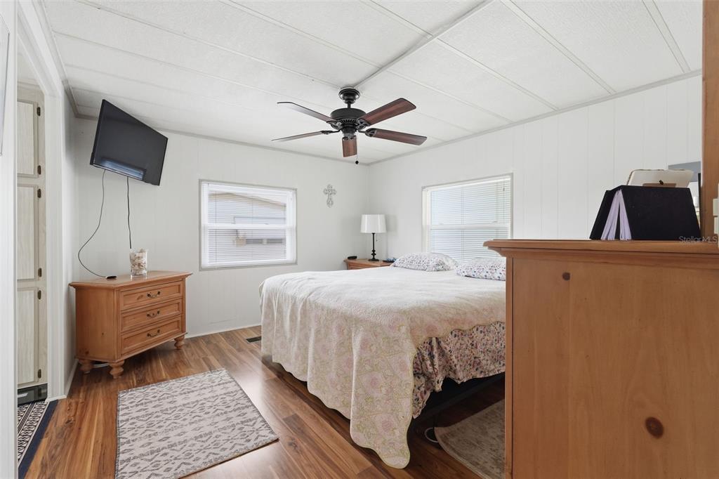 A bedroom features a bed, wooden furniture, a ceiling fan, and white paneled walls — 2049 MANOA DRIVE, HOLIDAY, FL