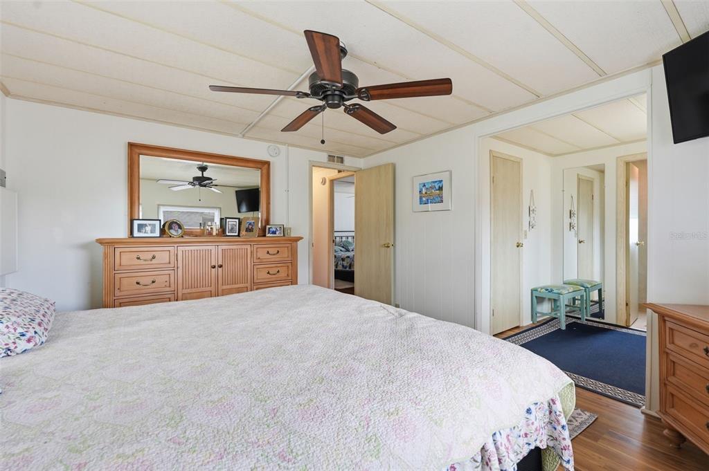 A bedroom features a wooden dresser with a mirror, a ceiling fan, and a doorway — 2049 MANOA DRIVE, HOLIDAY, FL