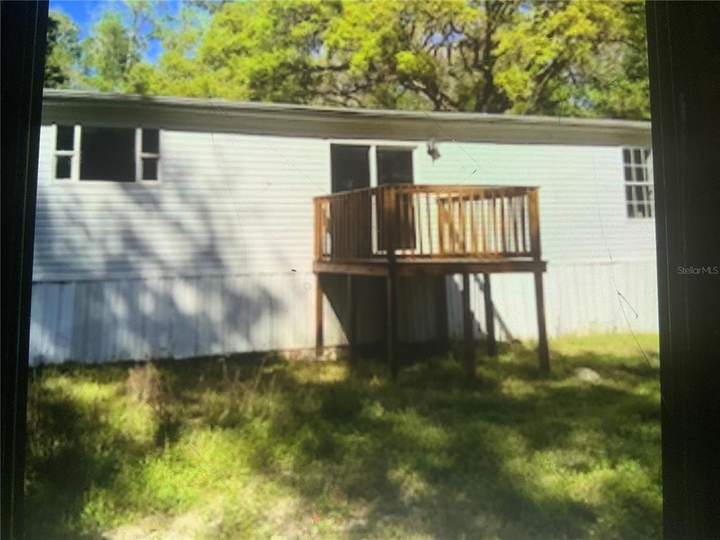 The exterior of a manufactured home features white siding and a wooden deck — 13080 NW 168TH PLACE, REDDICK, FL