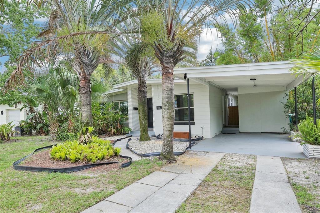 A single-story white house features a carport, palm trees, and a landscaped front yard — 318 E JERSEY STREET, ORLANDO, FL